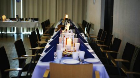 na zdjęciu stół dla gości odświetnie udekorowany niebieskie serwety białe obrusy lampiony z zapalonymi świecami