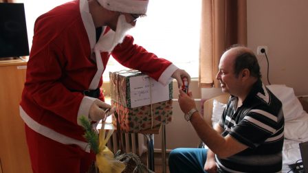 Na zdjęciu znajduje się Mieszkaniec otrzymujący prezent od Świętego Mikołaja.